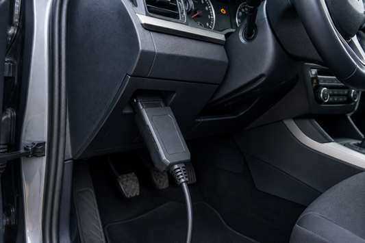 OBD2 scanner plugged into the diagnostic port beneath a vehicle dashboard