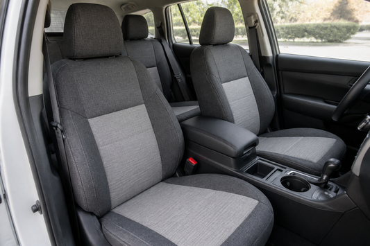 Universal seat covers fitted across a vehicle interior with headrests, seat belts, and seat controls left accessible